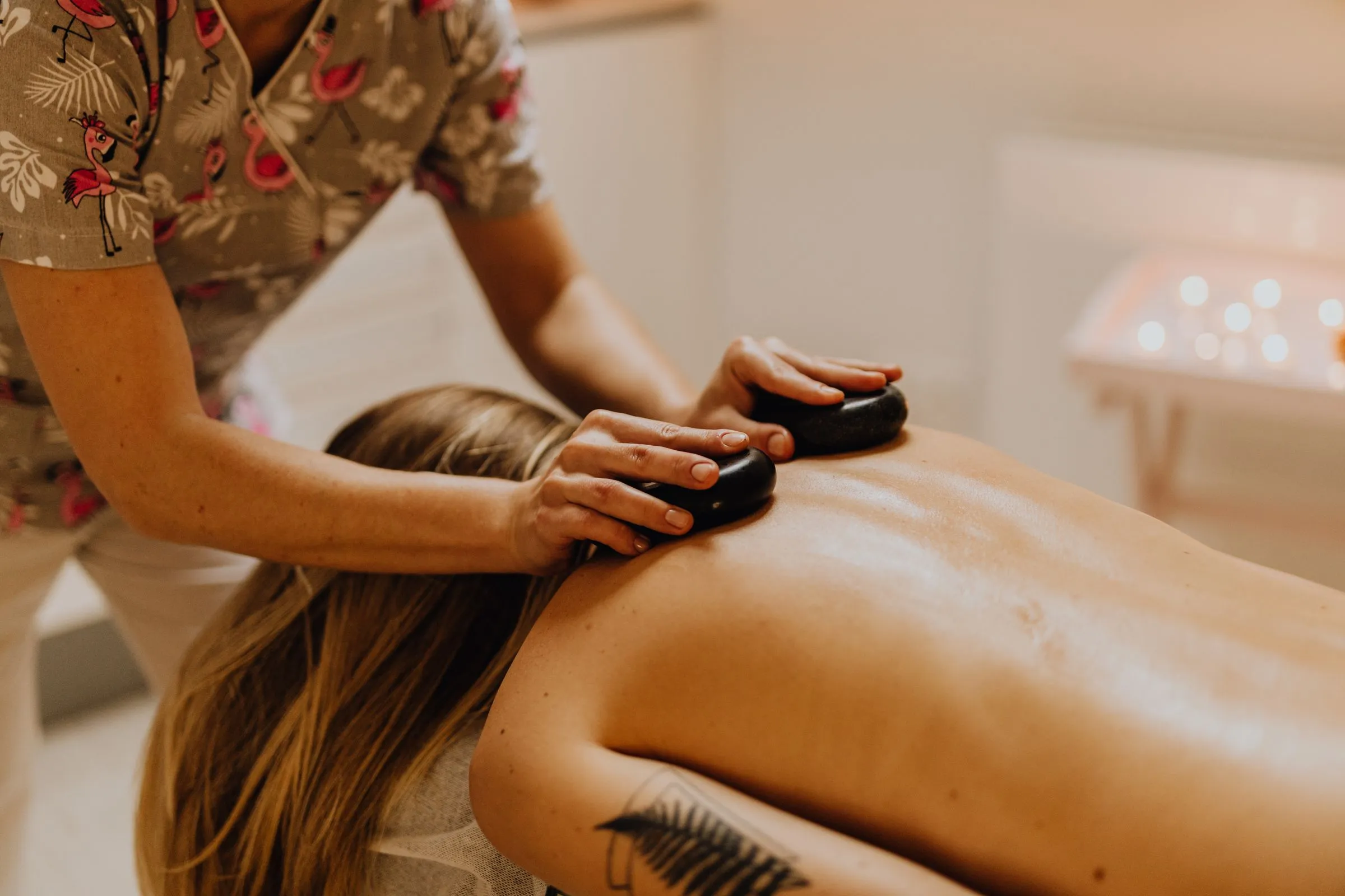 A therapist placing warm basalt stones along a client’s back