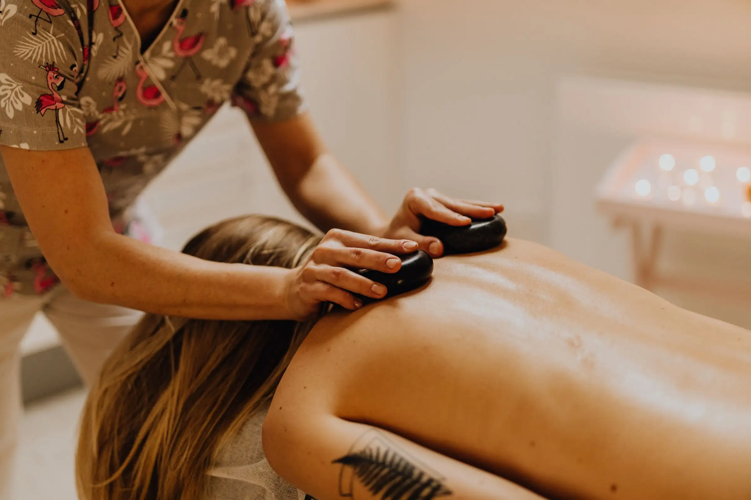 A therapist resting warm basalt stones along a client’s back